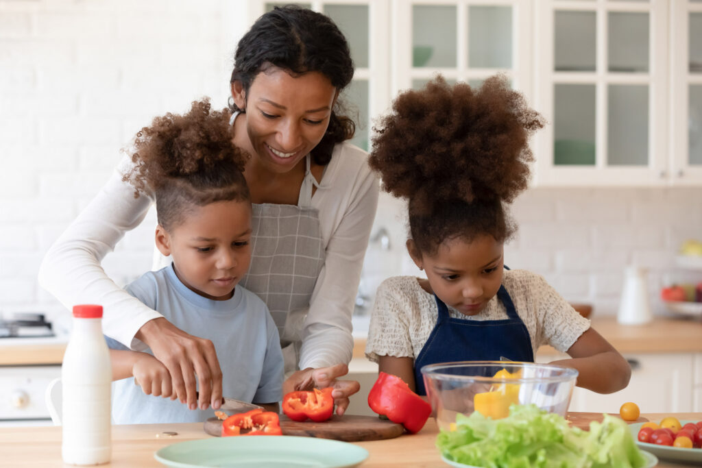 Happy mom teaching her children how to cook